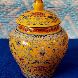 May include: A yellow ceramic jar with a lid, decorated with intricate floral patterns in blue, red, and gold. The jar has a traditional Chinese design.