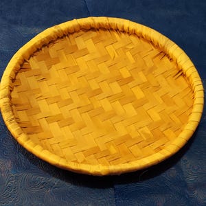 May include: A round, woven, light brown bamboo tray with a woven rim.