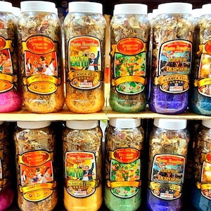 May include: A collection of clear plastic jars filled with coloured granules and dried herbs. Each jar has a white lid and a label with text and illustrations. The jars are displayed on shelves, showcasing a variety of products.