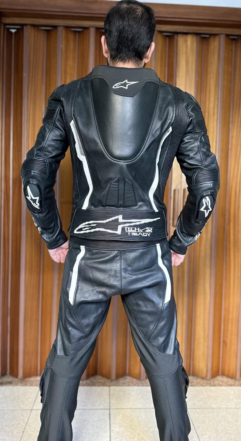 Op de afbeelding: Zwart leren motorpak met witte accenten en de tekst "Tech-Air Ready" op de taille.