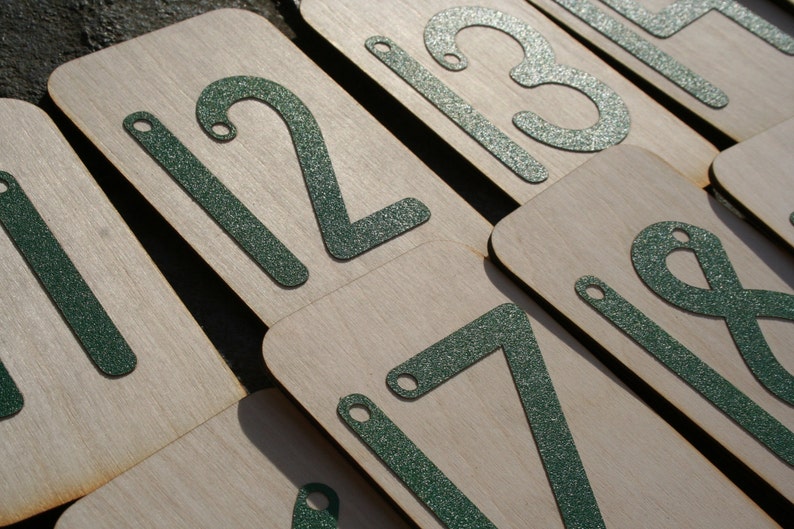 May include: A set of wooden number tiles with green glitter numbers. The numbers are 1, 2, 3, 7, and 8.
