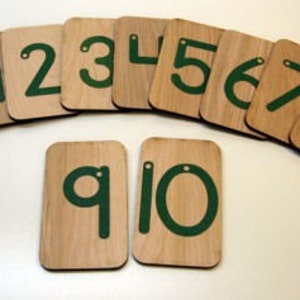 Puede incluir: Diez fichas de madera numeradas con n&uacute;meros verdes. Los n&uacute;meros son del 1 al 10.