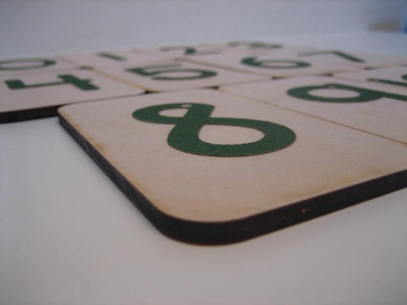 Puede incluir: Azulejos de madera con n&uacute;meros verdes sobre un fondo blanco. Los n&uacute;meros son 1, 2, 3, 4, 5, 6, 7, 8 y 9.