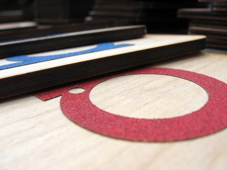 May include: Close-up of a wooden surface with a red circle cutout. The circle is outlined with a red, textured material.