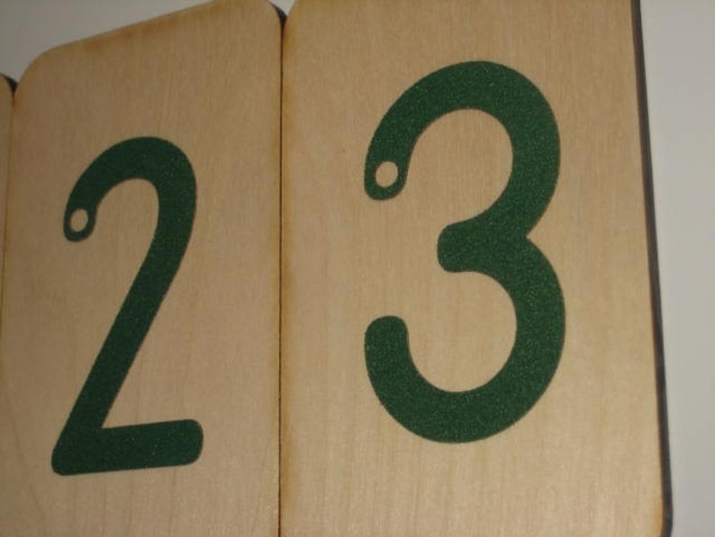 Puede incluir: Dos bloques de madera con los n&uacute;meros 2 y 3 impresos en verde. Los n&uacute;meros est&aacute;n delineados en blanco.