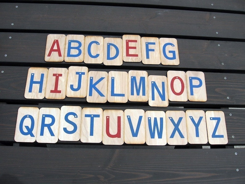 May include: Wooden alphabet blocks with blue and red painted letters. The letters are arranged in alphabetical order from A to Z.