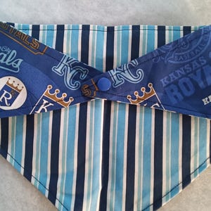 K&ouml;nnte beinhalten: Halsband f&uuml;r Haustiere mit dem Logo des Baseballteams Kansas City Royals. Das Bandana hat blaue und wei&szlig;e Streifen und einen Knopfverschluss. Die obere Schicht zeigt das Teamlogo, die untere Schicht hat vertikale Streifen.
