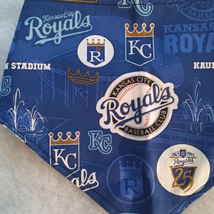 K&ouml;nnte beinhalten: Blau-wei&szlig;es Kansas City Royals Baseball-Team-Bandana. Das Bandana zeigt das Logo des Teams, die Worte "Kansas City Royals" und andere teambezogene Grafiken. Das Bandana ist aus einem weichen Stoff gefertigt.