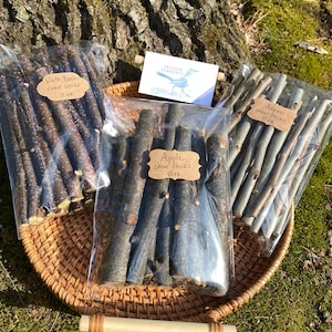 May include: Three bags of natural wood chew sticks for dogs. The bags are labeled "White Birch chew Sticks 10 oz", "Aspen chew Sticks 10 oz", and "Apple chew Sticks 10 oz".