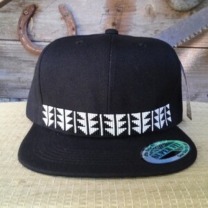 Puede incluir: Una gorra de béisbol negra con un patrón geométrico blanco alrededor de la banda. La gorra tiene una visera curvada y una corona estructurada.