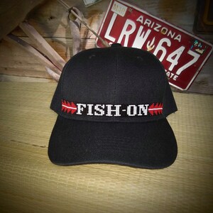 May include: Black baseball cap with a red and white beaded band that says "FISH-ON".