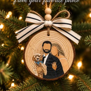 May include: A round wood slice ornament featuring a hand-painted illustration of a couple and a small dog. The ornament is topped with two wooden beads and a cream-coloured ribbon with thin black stripes. Text reads: HAND-PAINTED CUSTOM ORNAMENTS from your favourite photo. MADE WITH LOVE. MADE FOR MEMORIES.