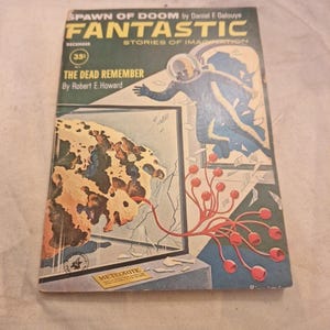 Könnte beinhalten: Vintage-Ausgabe des Magazins "Fantastic" mit einem Cover, das einen Astronauten und eine kosmische Szene zeigt. Der Text auf dem Cover lautet "Spawn of Doom" und "The Dead Remember." Das Kunstwerk ist in Blau, Orange und Grün gehalten, mit einem Preis von 35 Cent.