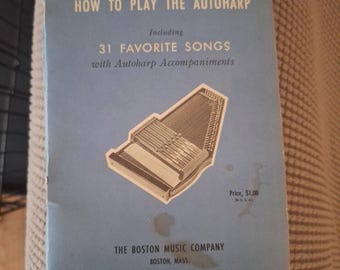 May include: A blue book titled "Frances Hall's How to Play the Autoharp" with a picture of an autoharp and the text "Including 31 Favorite Songs with Autoharp Accompaniments". The book is published by The Boston Music Company.