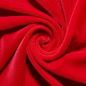 May include: Close-up of a vibrant red velvet fabric, tightly swirled to create a spiral pattern. The plush material reflects light, highlighting its soft texture and rich color. The fabric's folds and curves create a dynamic visual effect.