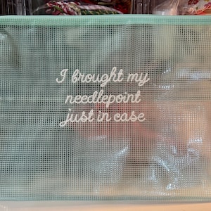 May include: A light green, mesh-textured zippered pouch with the text "I brought my needlepoint just in case" in white script. The pouch is rectangular and appears to be made of a durable, semi-transparent material, ideal for storing craft supplies.