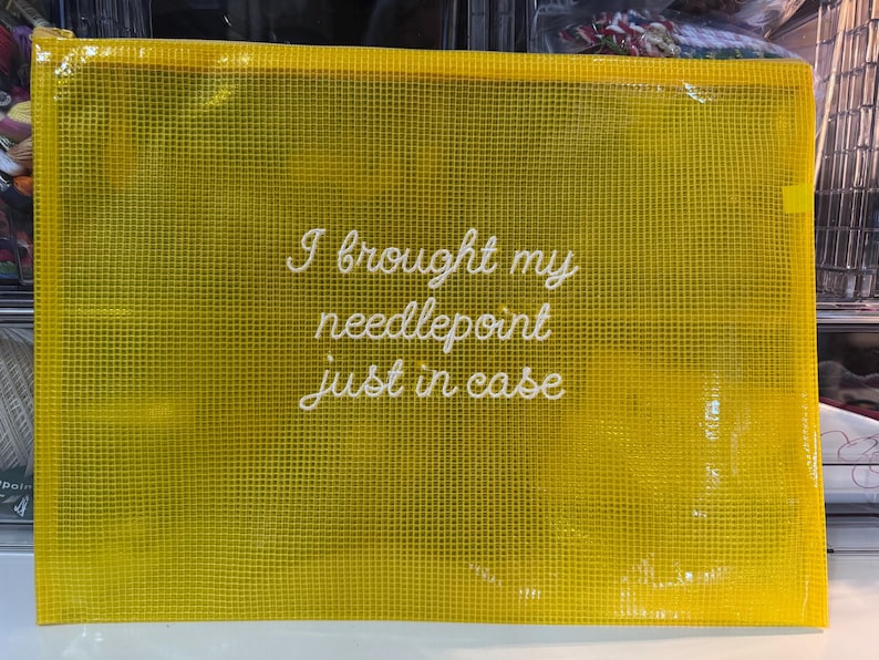 May include: A yellow mesh zippered pouch with the text "I brought my needlepoint just in case" in white script. The pouch is rectangular and appears to be made of a durable, see-through material, suitable for storing craft supplies.