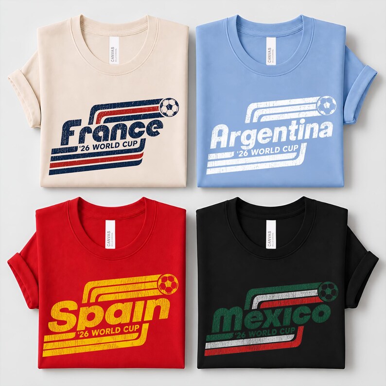 May include: Four t-shirts in beige, light blue, red, and black, each featuring a distressed graphic with a soccer ball and the text '26 WORLD CUP' alongside the country names France, Argentina, Spain, and Mexico in a retro striped design.