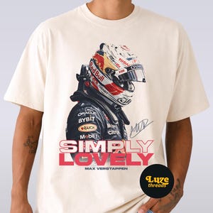 Puede incluir: Camiseta color crema con un gr&aacute;fico de un piloto de F&oacute;rmula 1 con un casco Red Bull. El dise&ntilde;o incluye el texto "SIMPLY LOVELY" en rosa y rojo, y "MAX VERSTAPPEN". Tambi&eacute;n es visible una firma. La camiseta es de "Luze threads".