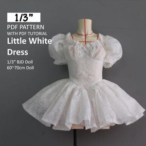 May include: White lace dress for a 1/3 scale BJD doll, 60-70 cm tall. The dress has a ruffled neckline and puffed sleeves. The skirt is full and layered.