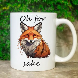 Könnte beinhalten: Weiße Keramik-Kaffeetasse mit einer Fuchs-Illustration und dem Text "Oh for sake".