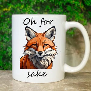 Könnte beinhalten: Weiße Keramiktasse mit einer Illustration eines roten Fuchses und dem Text "Oh for sake" in Schwarz.