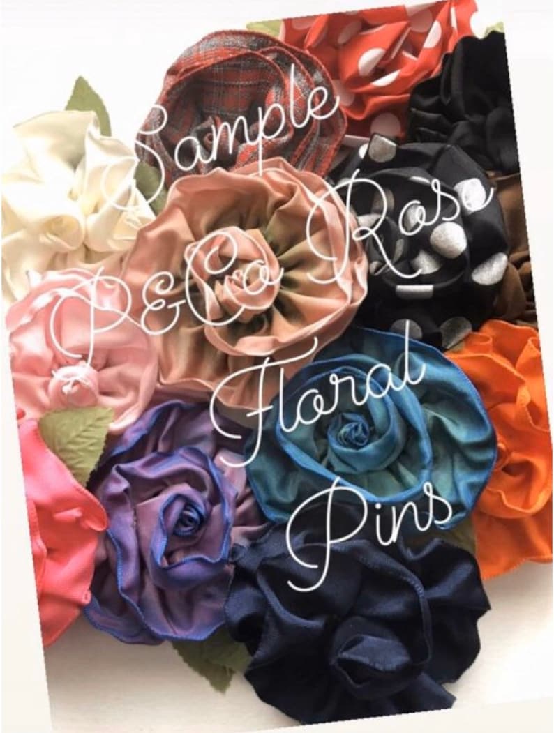 Puede incluir: Una colecci&oacute;n de pinzas para el pelo de flores de tela en varios colores y patrones, incluyendo rojo, blanco, negro, azul, verde y marr&oacute;n. Las flores est&aacute;n dispuestas en forma de ramo y tienen un dise&ntilde;o en capas y con volantes. El texto "Sample Rose P&Co Floral Pins" est&aacute; escrito en la imagen.