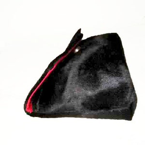 May include: A black velvet hat with a red trim. The hat has a pointed shape and a small button on the top.