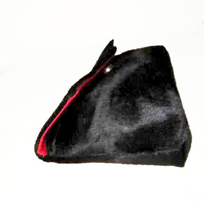 May include: A black velvet hat with a red trim. The hat has a pointed shape and a small button on the top.