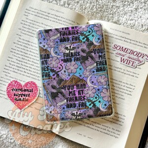 May include: A Kindle case with a colorful design featuring the text "YOU HAD ME AT FAERIES AND FAE". The case has a purple, blue, and white floral pattern with mountains, stars, and bats.