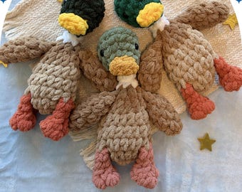 May include: Three handmade crochet mallard duck toys. The ducks have brown bodies, orange feet, and green, black, and olive green heads with yellow beaks. The text "mars the mallard" and "finished lovey" is visible.