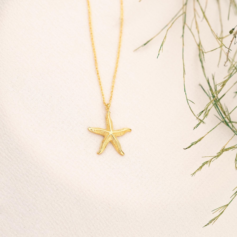 May include: A gold chain necklace with a gold starfish pendant