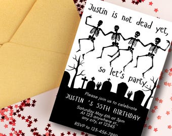 May include: A white invitation card with black text and a yellow envelope. The card features dancing skeleton figures and the text "Justin is not dead yet, so let's party." It is an invitation for Justin's 55th birthday.