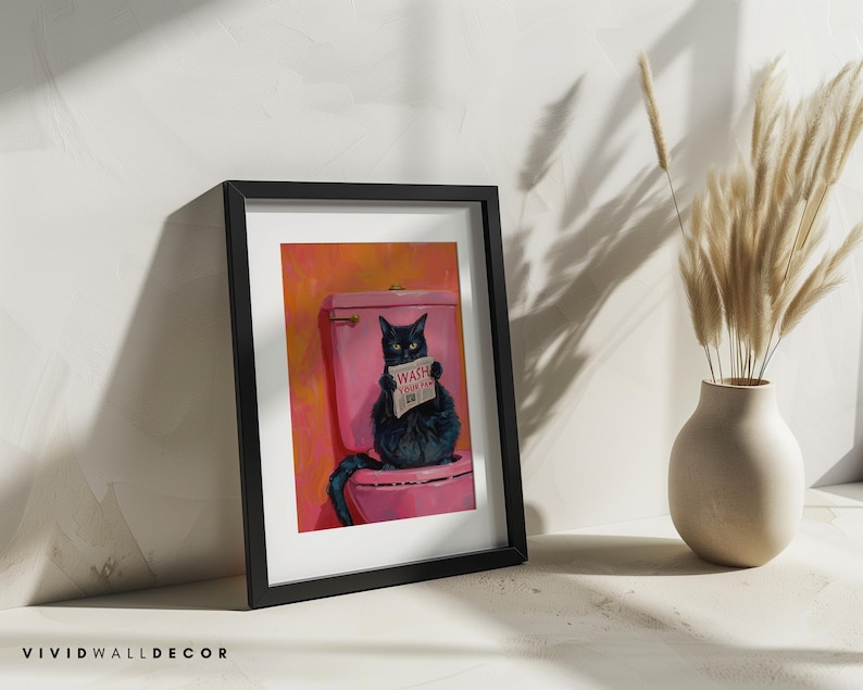 May include: A framed painting of a black cat sitting on a pink toilet with a sign that says "Wash Your Paws" in a bathroom setting.