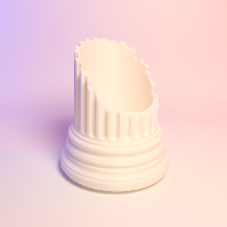 May include: A white cylindrical holder featuring a fluted column design with a stepped base and a jagged, uneven top edge. The object has a matte finish and a hollow center, resembling a broken piece of classical architecture or a pillar.