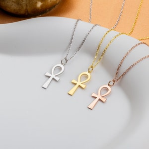 May include: Four gold, silver, and rose gold necklaces with an ankh pendant. The necklaces are on a white surface.