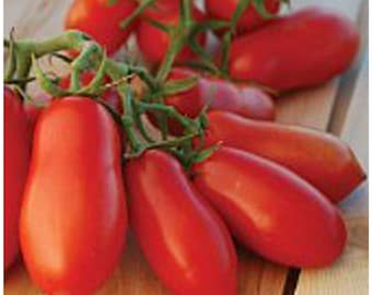 May include: A bunch of red, ripe Roma tomatoes on a wooden surface. The tomatoes are oval-shaped and have a smooth skin.