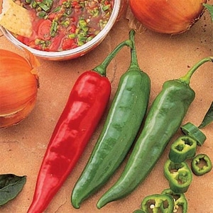 May include: A vibrant image showcasing fresh ingredients for a meal. A red chili pepper, two green chili peppers, and sliced peppers are arranged on a brown surface. A bowl of salsa and an onion are also visible.