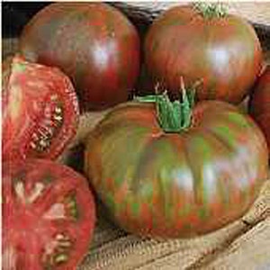 May include: Close-up of four heirloom tomatoes. The tomatoes are a deep red color with green and black streaks. The tomatoes are arranged on a burlap surface.