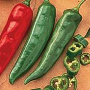 May include: Three whole chili peppers, one red and two green, with sliced green chili peppers in the background.