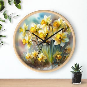 Könnte beinhalten: Eine runde Wanduhr mit Holzrahmen und weißem Hintergrund, auf dem eine Aquarellmalerei von gelben Narzissen zu sehen ist.