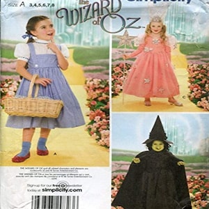 Puede incluir: Un sobre de patrón de costura Simplicity para disfraces de El Mago de Oz, que presenta tres diseños: un vestido de pichi a cuadros vichy azul y blanco, un vestido de hada rosa adornado con estrellas con alas y varita, y un disfraz de bruja negro.