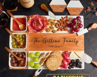 May include: A wooden and marble serving board with a personalized inscription "The Gillian Family Est. 2023". The board is filled with various snacks, including grapes, cheese, crackers, and salami.