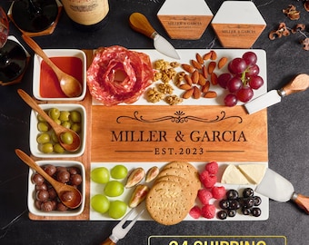 May include: A personalized wooden and marble serving board with a white background and a brown wooden frame. The board has a compartment for olives, a compartment for chocolate candies, and a compartment for grapes. The board also has a section for salami, almonds, walnuts, grapes, raspberries, blueberries, and crackers. The board is engraved with the text "Miller & Garcia Est. 2023".