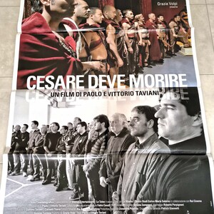 Può includere: Un poster del film "Cesare Deve Morire" (Cesare deve morire) con un'immagine in bianco e nero di uomini. Il titolo è in grandi lettere bianche. Il poster include testo sulla produzione e sui premi del film.