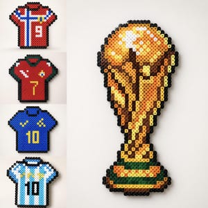 May include: A collection of five pixel art pieces made from plastic beads. Four pieces are shaped like sports jerseys in red, blue, and white with various numbers, and one large piece is shaped like a gold trophy with a green base.