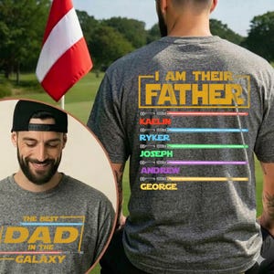 May include: A grey t-shirt with the text "I AM THEIR FATHER" and the names KAELIN, RYKER, JOSEPH, ANDREW, and GEORGE below. The shirt also has the text "THE BEST DAD IN THE GALAXY" on the front. A man is wearing the shirt.