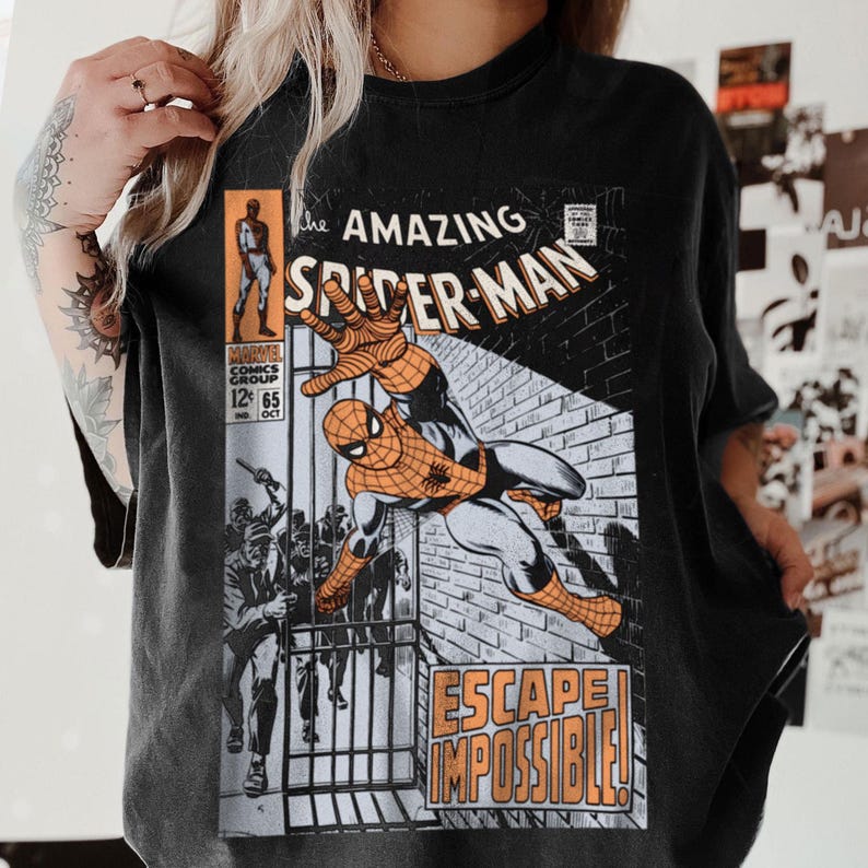 May include: Black t-shirt featuring a vintage comic book cover of Spider-Man. The graphic includes the title "The Amazing Spider-Man" and the phrase "Escape Impossible!" in orange and white. The comic book cover art depicts Spider-Man in action.