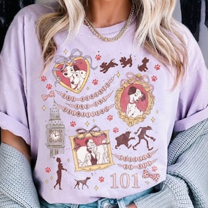 May include: A light purple t-shirt featuring illustrations of Dalmatian dogs and the text "ONE HUNDRED ONE DALMATIANS". The design includes framed portraits, paw prints, and the Big Ben clock tower.