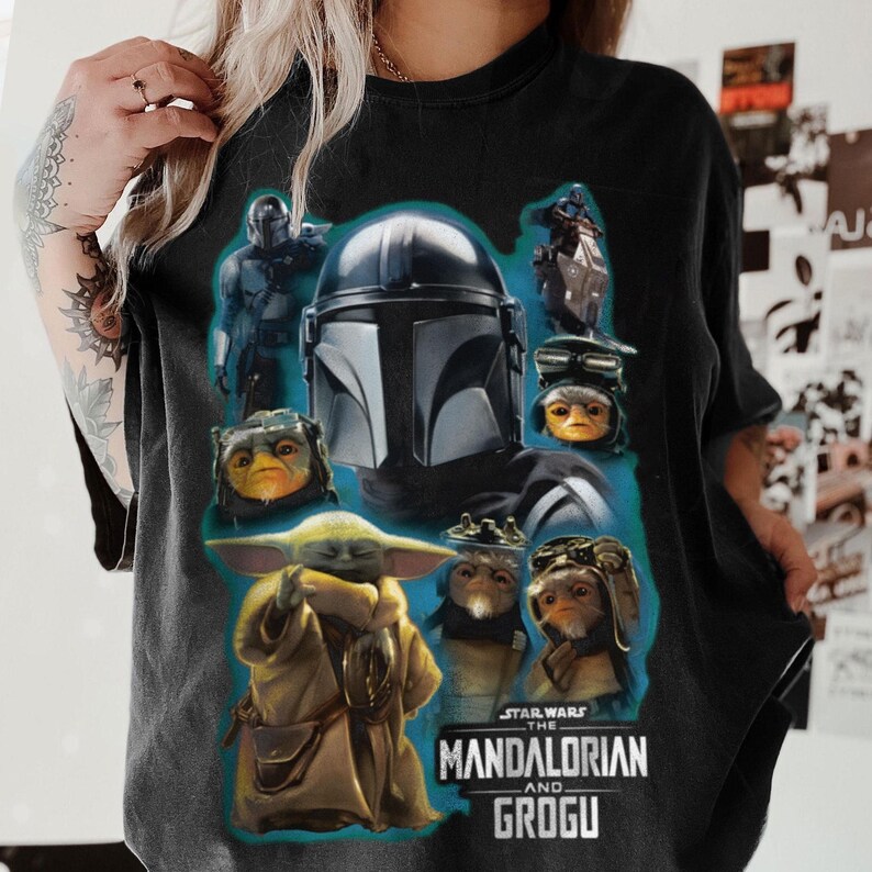 Puede incluir: Camiseta negra con un gr&aacute;fico de personajes de The Mandalorian y Grogu. El dise&ntilde;o incluye el casco del Mandaloriano, Grogu y otros personajes en una combinaci&oacute;n de colores azul y gris. El logotipo de Star Wars est&aacute; en la parte inferior.